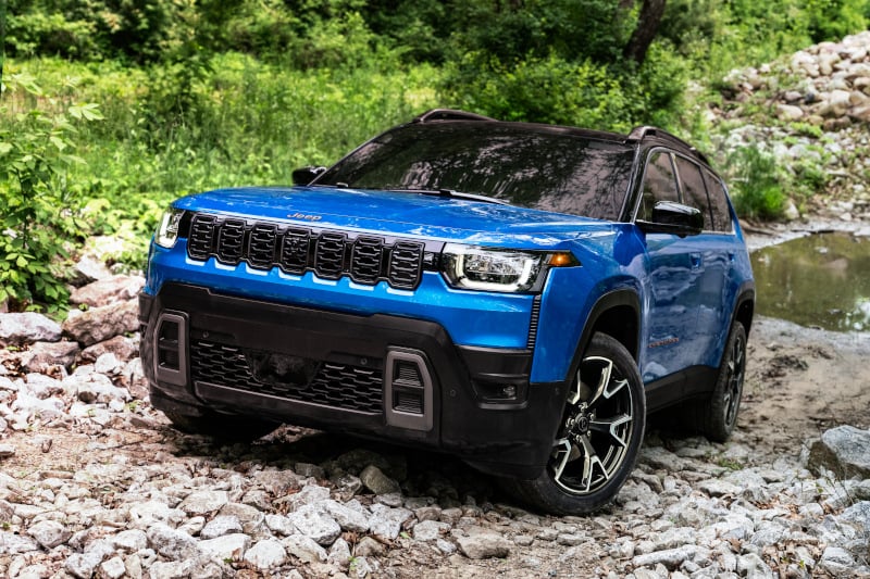 Jeep Cherokee 2026 bleu sur une route en forêt