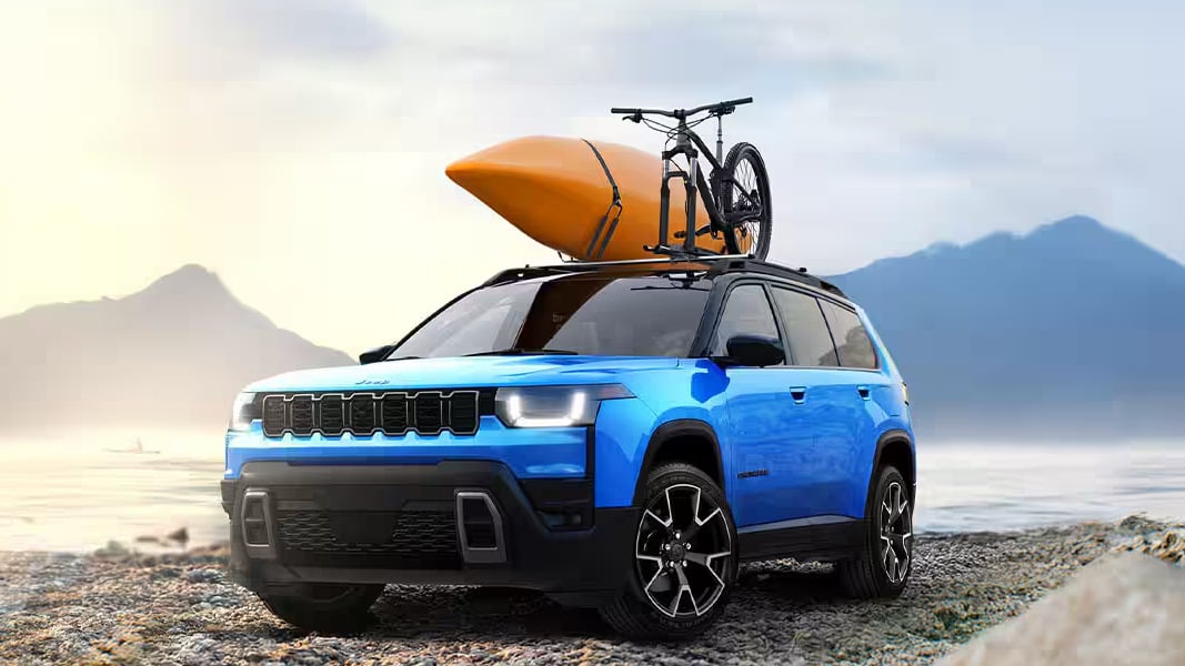 Jeep Cherokee 2026 de couleur bleu sur une berge avec phares allumés
