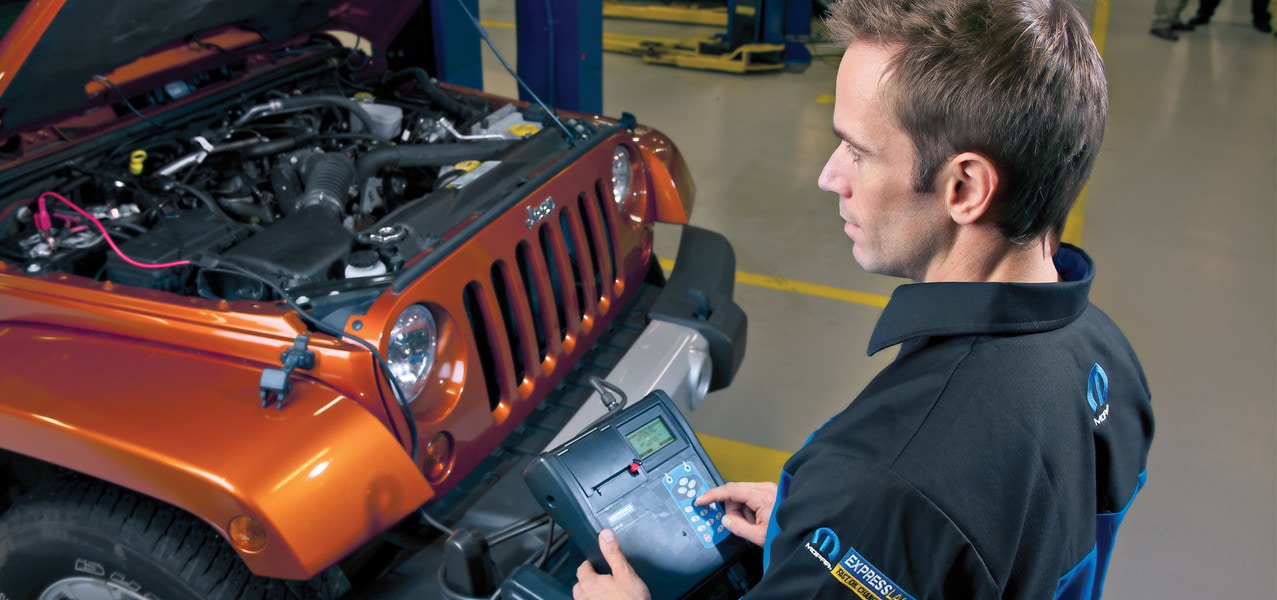 A mechanic looking under the hood of a Jeep