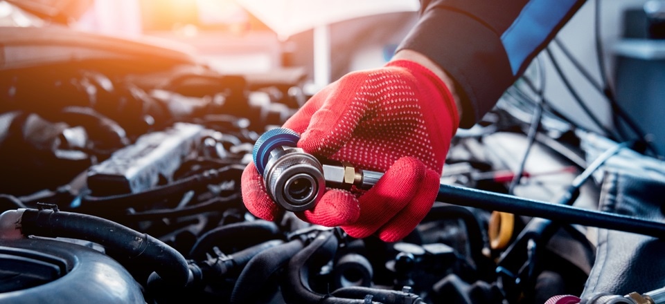 Hand in a red work glove servicing a car