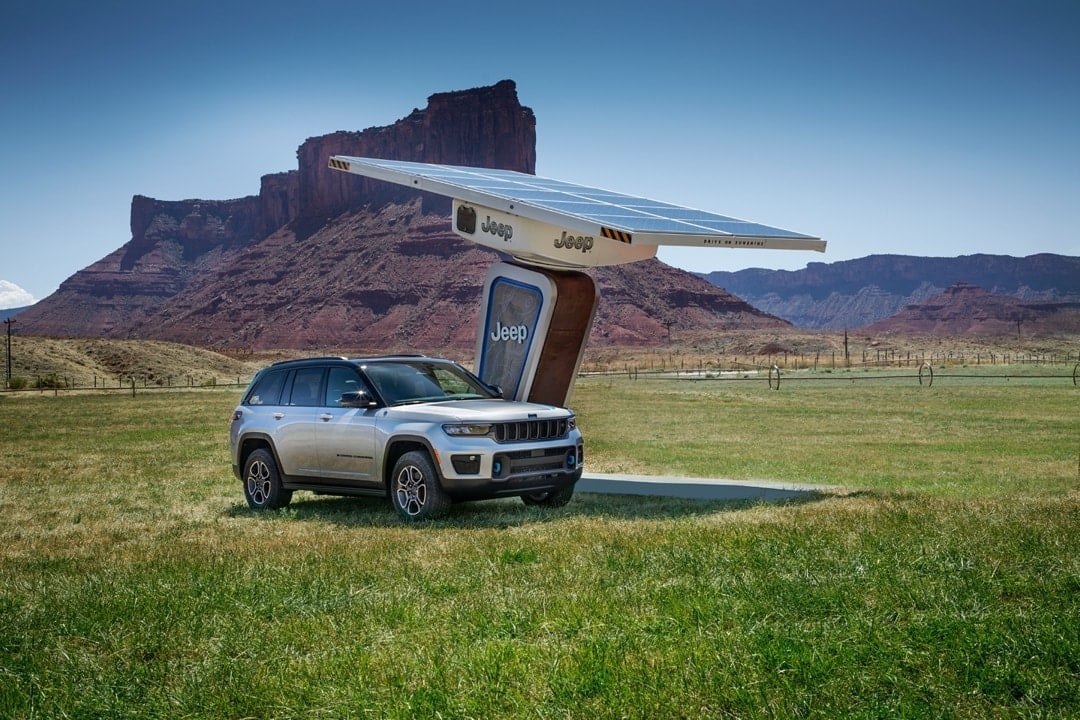 Le Jeep Grand Cherokee 4xe 2023 en recharge de batterie sur une station électrique extérieure.