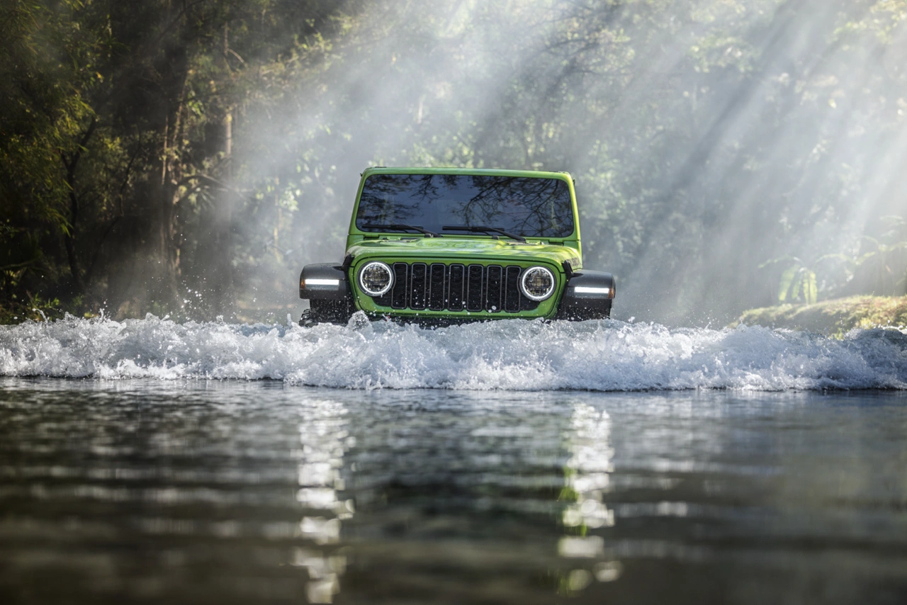 The 2026 Jeep Wrangler driving through the middle of a river.